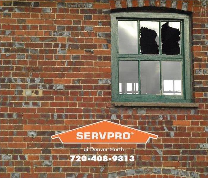 Two broken windowpanes are shown in the window of a commercial building.